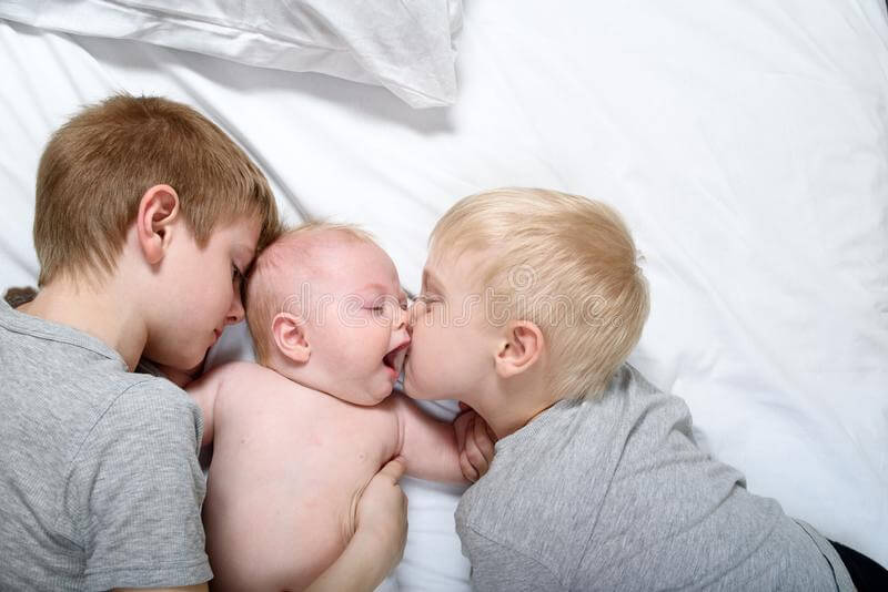 two-older-brothers-tenderly-kiss-hug-younger-child-white-bed-happy-family-166455663.jpg